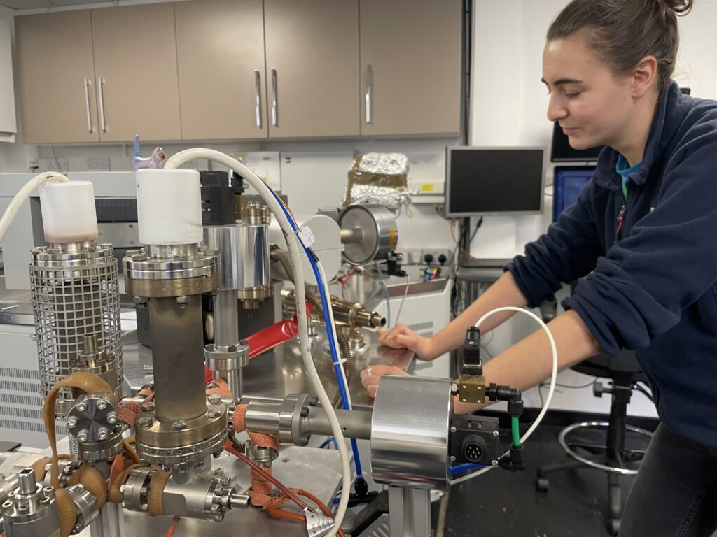 Photo of a woman infront of a Split Flight Tube KMass Spectrometer